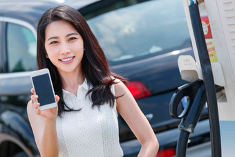 青年女人使用手机自助充电汽车