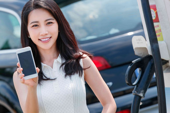 青年女人使用手机自助充电汽车