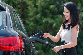 漂亮的青年女人给<strong>汽车</strong>充电