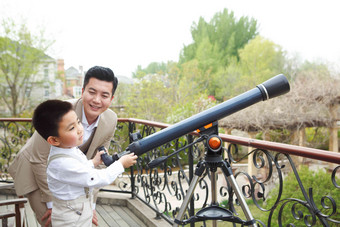 父亲和儿子在阳台使用天文<strong>望远</strong>镜探险高质量摄影图
