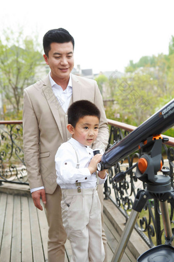 父亲和儿子在阳台使用天文望远镜城市生活高质量素材