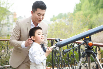 父亲和儿子在阳台使用天文望远镜欢乐高清素材