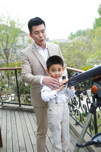 父亲和儿子在阳台使用天文望远镜乐趣氛围影相