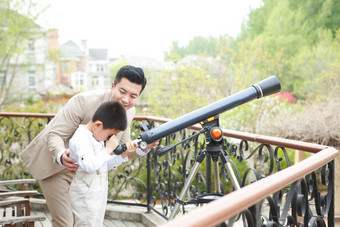 父亲和儿子在阳台使用天文望远镜放松高端素材