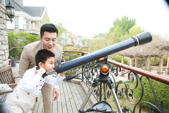 父亲和儿子在阳台使用天文望远镜丰富写实摄影