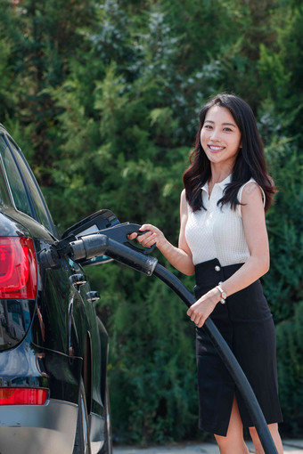 漂亮的青年女人给<strong>汽车</strong>充电