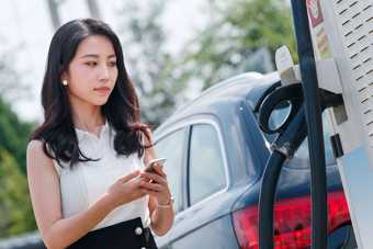 青年女人使用手机自助充电<strong>汽车</strong>