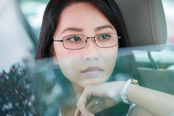 青年女人坐在汽车里向外看眼镜高清素材