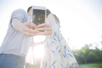 青年手机照相男人亲吻女朋友写实影相