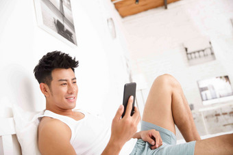 青年男人在卧室玩手机摄影高清摄影图