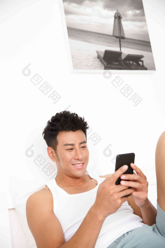 青年<strong>男</strong>人在卧室玩手机成年人写实素材