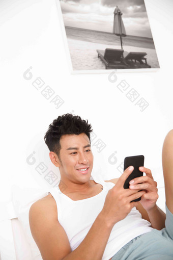 青年男人在卧室玩手机东方人氛围相片
