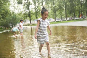 快乐儿童在户外蹚水玩三个人氛围摄影图