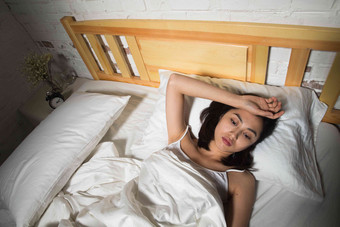 青年女人躺在床上失眠枕头高质量照片