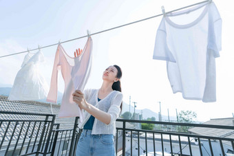 青年女人晾晒衣服微笑的高端场景