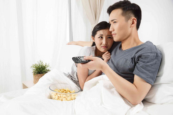 青年情侣坐着床上看<strong>电视</strong>被子清晰场景