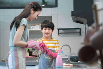 年轻妈妈指导儿子在厨房打扫卫生围裙氛围照片