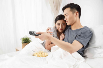 青年情侣坐着床上看电视女人氛围素材