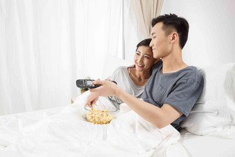 青年情侣坐着床上看<strong>电视</strong>中国人高质量摄影图
