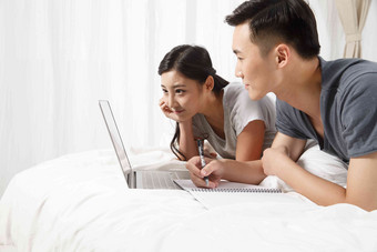 青年情侣趴在床上看电脑成年人高清图片