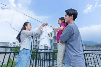 年轻爸爸抱着女儿和妈妈一起晾<strong>衣服</strong>