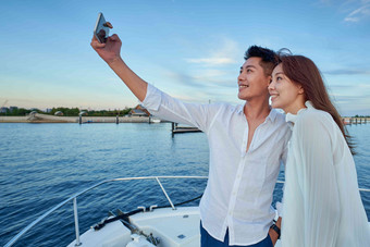 青年夫妇站在游艇上用<strong>手机</strong>拍照两个人高端场景