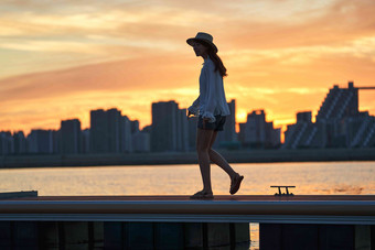 夕阳下在海边的青年女人