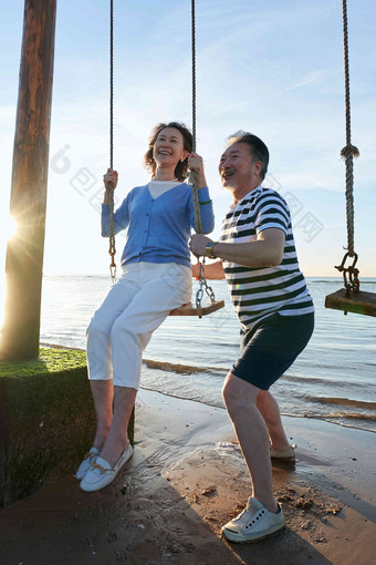 快乐的老年夫妇在海边荡秋千