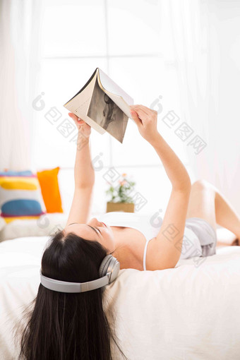 青年女人躺在床上听音乐<strong>看书</strong>音乐高质量素材