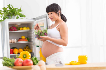 孕妇打开冰箱拿蔬菜