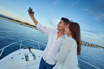 青年夫妇站在游艇上用手机拍照男人氛围摄影