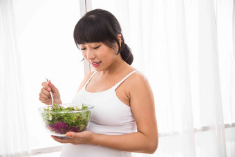 幸福的孕妇吃蔬菜沙拉吃高质量摄影图