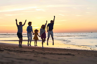 家庭海边度假儿童跳跃日落高质量图片