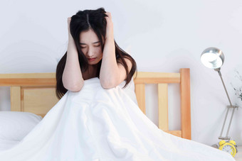 情绪低落的青年女人坐在卧室的床上棉被素材