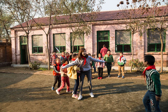 乡村教师和小学生在学校里做游戏破旧的氛围摄影图
