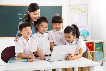 教师和小学生在教室里使用电脑成长高清照片