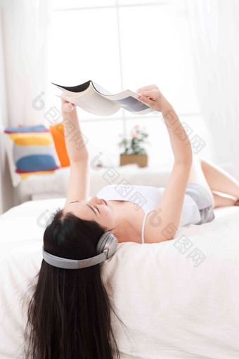 青年女人在卧室的床上听音乐