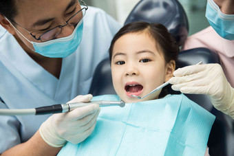 男牙医和女牙医助手在为小女孩检查牙齿青年人高清图片