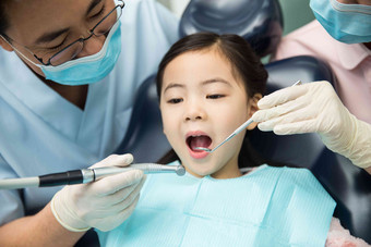 男牙医和女牙医助手在为小女孩检查牙齿团队高清场景