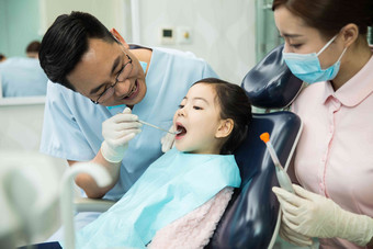 男<strong>牙医</strong>和女<strong>牙医</strong>助手在为小女孩检查牙齿