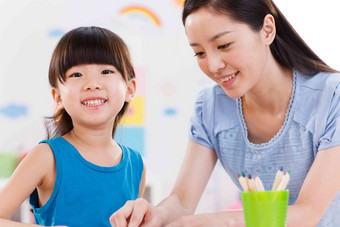 幼儿园里教师在指导女孩学习