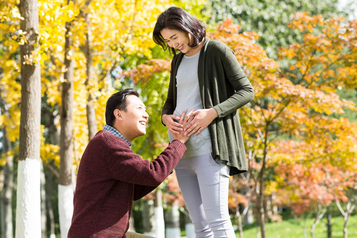 丈夫陪着怀孕的妻子在户外度假摄影