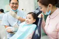 男牙医和女牙医助手在为小女孩检查牙齿