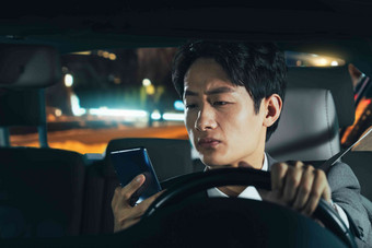 驾驶汽车的青年男人使用手机
