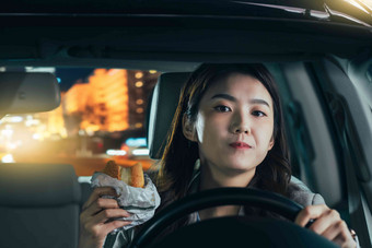 驾驶汽车的青年女人吃食物