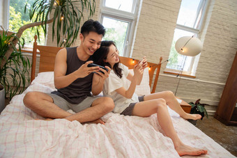 青年手机玩游戏妻子住宅内部高端素材