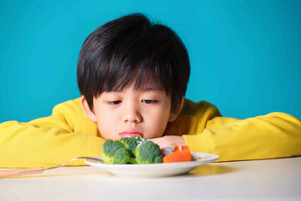 <strong>盯着</strong>蔬菜发愁的小男孩健康食物清晰拍摄