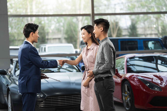 汽车销售人员和青年夫妇握手消费氛围摄影