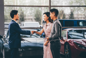汽车销售人员和青年<strong>夫妇握手</strong>站着清晰摄影