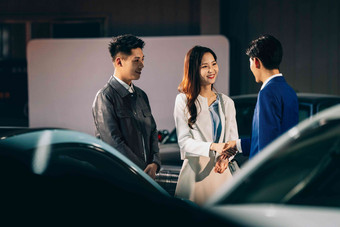 汽车销售人员和青年夫妇握手彩色图片高清拍摄